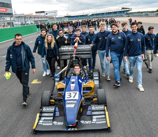 MoRe Modena Racing team members walking behind their car on the pit straight of Silverstone circuit